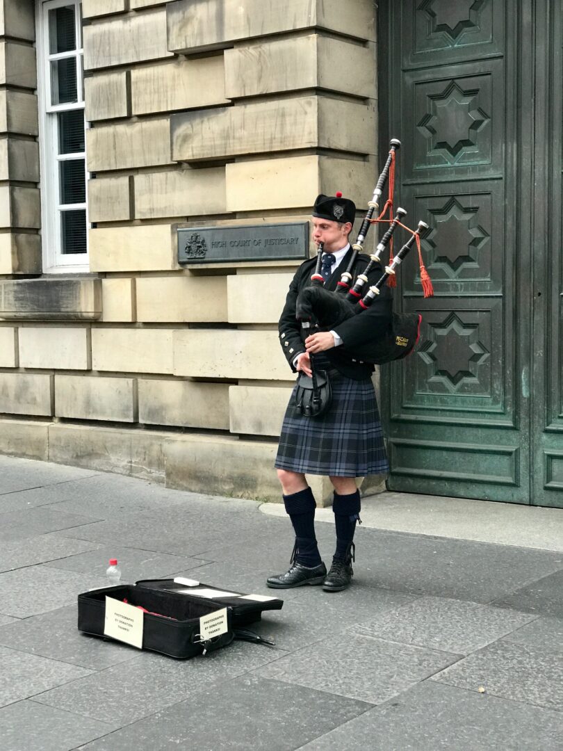 a man playing musical instruments in Scottish dress