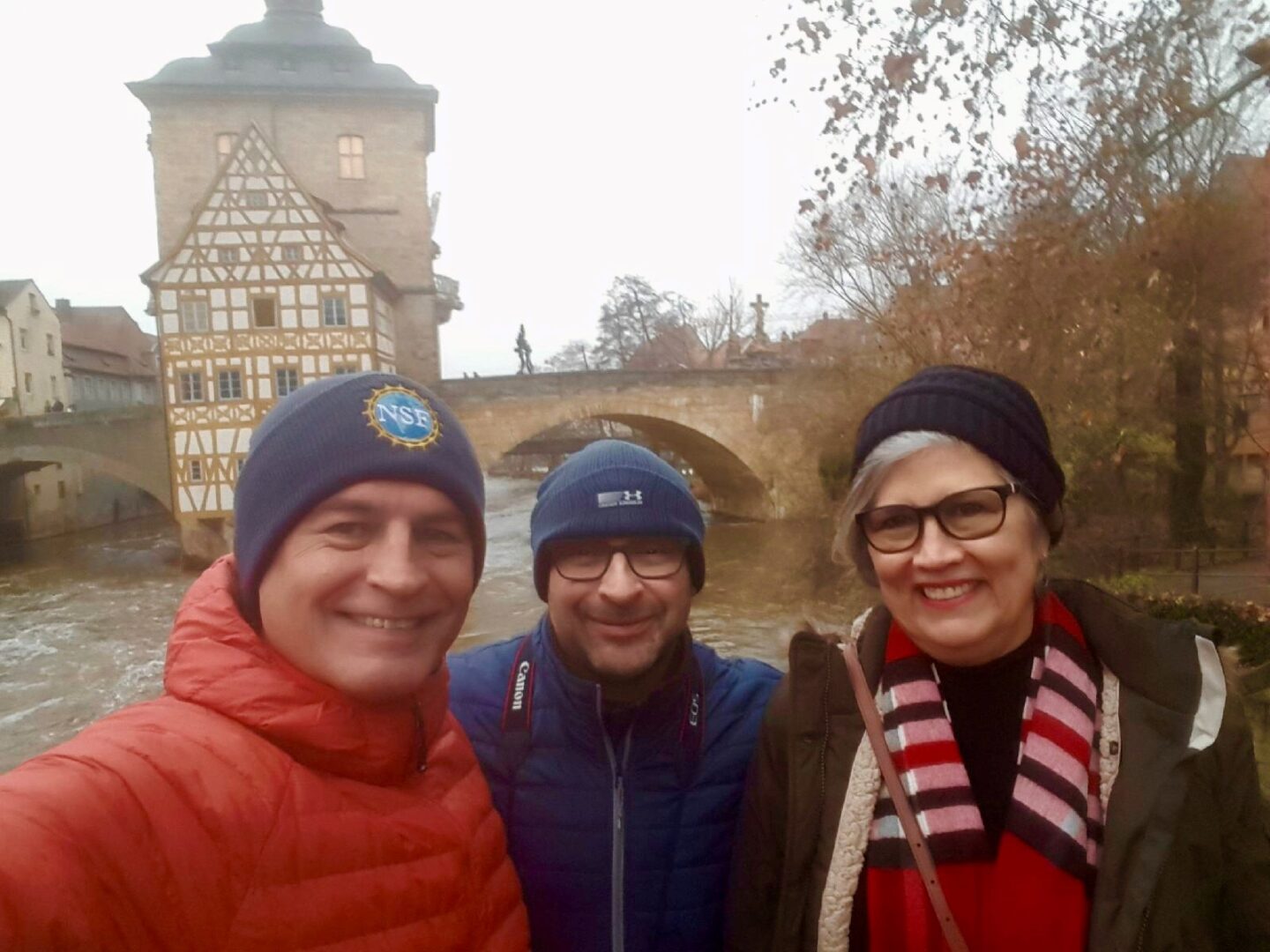 three tourists clicking selfie at a historic bridge